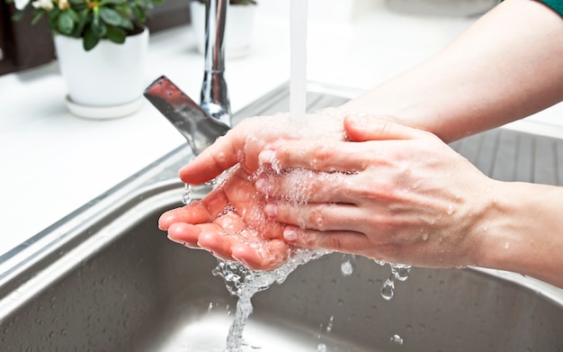 A mulher está lavando as mãos sob o fluxo de água em sua cozinha | Foto ...