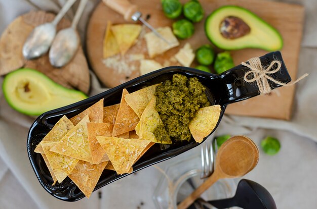 Abacate, couve de bruxelas, queijo parmesão e batatas fritas com molho pesto em prato incomum de servir. Foto Premium