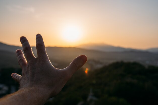 Abra a mão na direção do horizonte com um belo pôr do sol Foto Premium