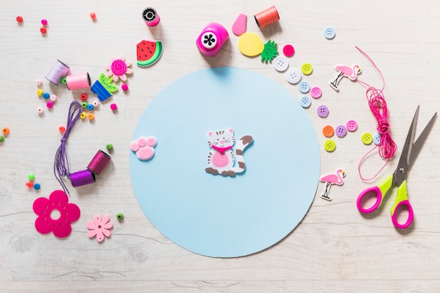 Adesivo de gato e pata no papel circular azul com itens decorativos em plano de fundo texturizado Foto gratuita