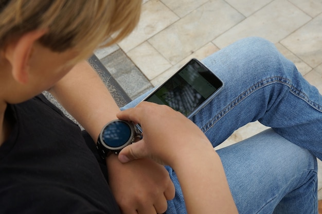 Adolescente conectando seu samrtwatch com seu smartphone Foto Premium