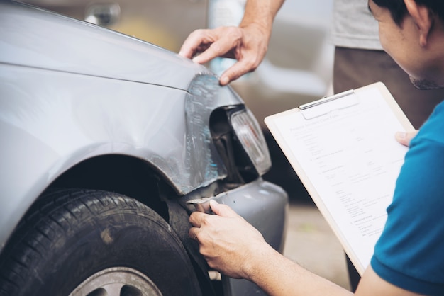 Agente de seguros que trabalha durante processo de reivindicação de acidente de carro no local, reclamação de seguro de pessoas e de carro Foto gratuita