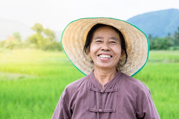 Agricultor feminino tailandês feliz sorrindo sobre fazenda de arroz verde | Foto Premium