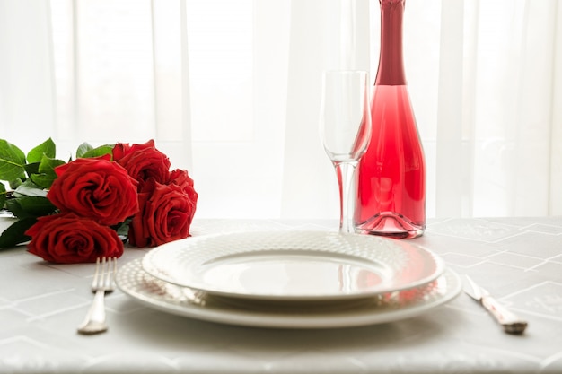 Ajuste de lugar da tabela do dia de valentim com rosas vermelhas e champanhe. convite para uma data. Foto Premium