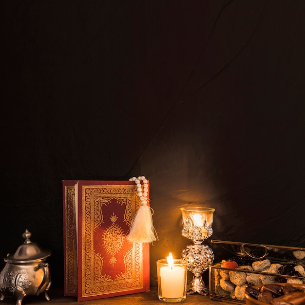 Alcorão e velas perto de doce Foto gratuita
