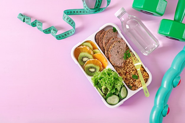 Almoço saudável com bulgur, carne e legumes frescos e frutas em um fundo rosa. Foto Premium