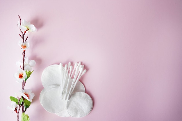 Almofadas de algodão e cotonetes com flores brancas em fundo rosa pastel Foto Premium