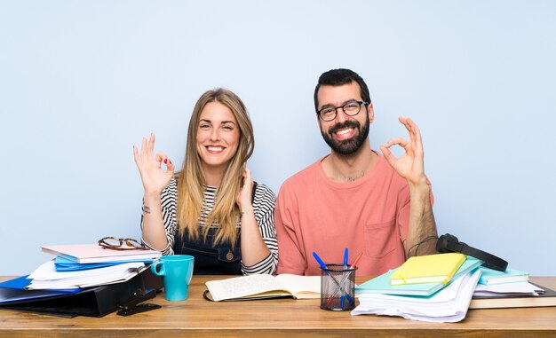 Alunos com muitos livros mostrando sinal de ok com os dedos Foto Premium
