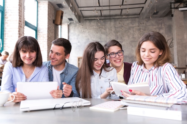 Alunos sentados à mesa e estudando com livros e tablet Foto gratuita