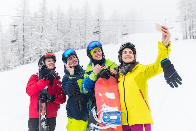 Amigos, com, esqui, e, snowboard, levando, um, selfie, ligado, a, declives Foto Premium