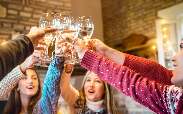 Amigos felizes comemorando o natal brindando com champanhe vinho em casa jantar Foto Premium