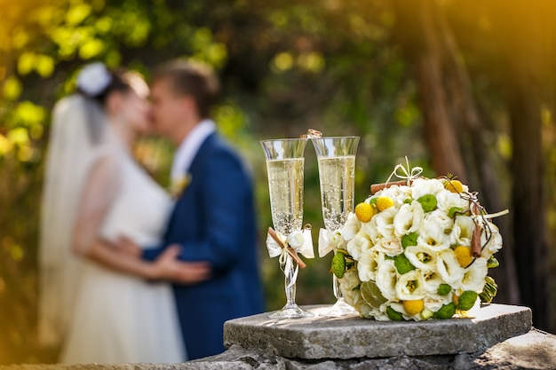 Anéis de casamento com rosas e taças de champanhe e um beijo do noivo e da noiva Foto Premium