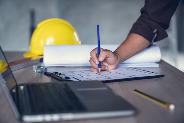 Arquiteto e engenheiro trabalhando documento de desenho sobre o planejamento do projeto e o andamento do cronograma de trabalho no canteiro de obras de construção civil Foto Premium