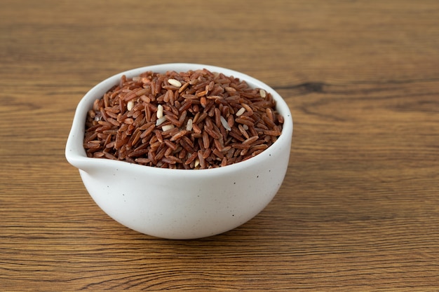 Arroz integral para tigela branca saudável em fundo de madeira Foto Premium