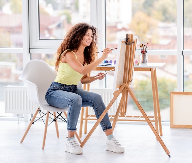 Artista sorridente pintura em cavalete Foto Premium