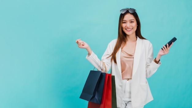 As blogueiras asiáticas de belas mulheres estão usando o smartphone para fazer compras on-line com uma sacola de compras. Foto Premium