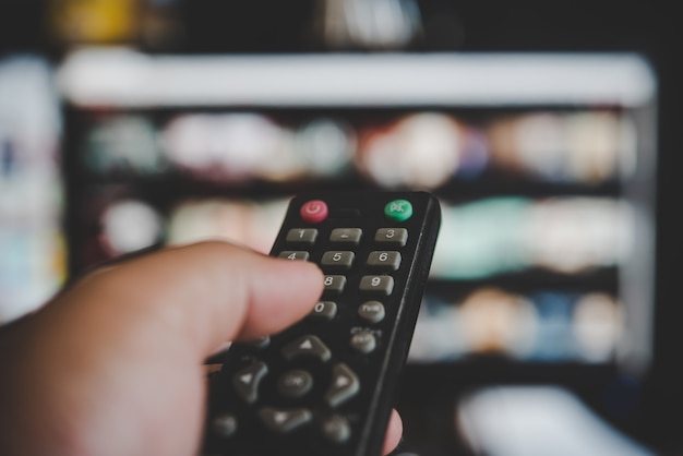 Assistir televisão, com o controle remoto da tv na mão | Foto Premium
