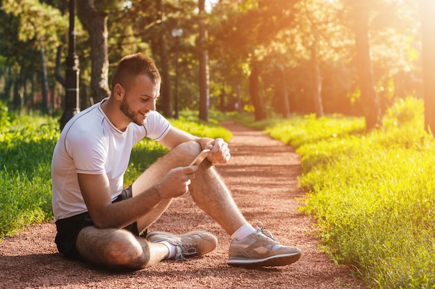 Atleta ou treinador esportivo verificando seu telefone celular no parque Foto Premium