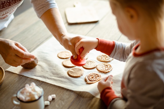 Avó e neta de manhã no mesmo pijama juntos assam selos de biscoitos de natal no teste. o acolhedor conceito de natal da família. Foto Premium