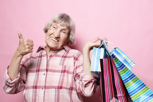 Avó feliz com sacos de compras sobre fundo rosa. estilo de vida e conceito de pessoas. Foto Premium