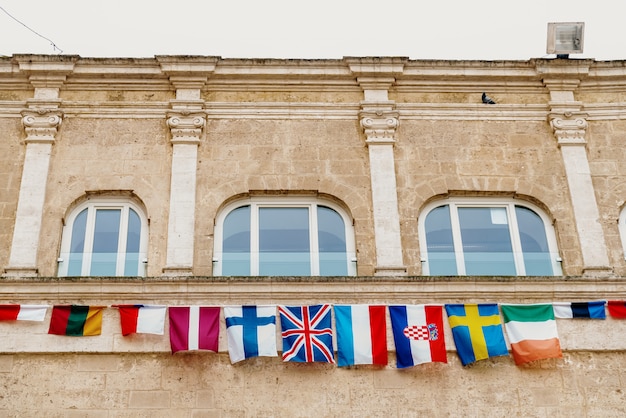 Bandeiras dos países europeus que penduram de um balcão na cidade italiana de matera. Foto Premium
