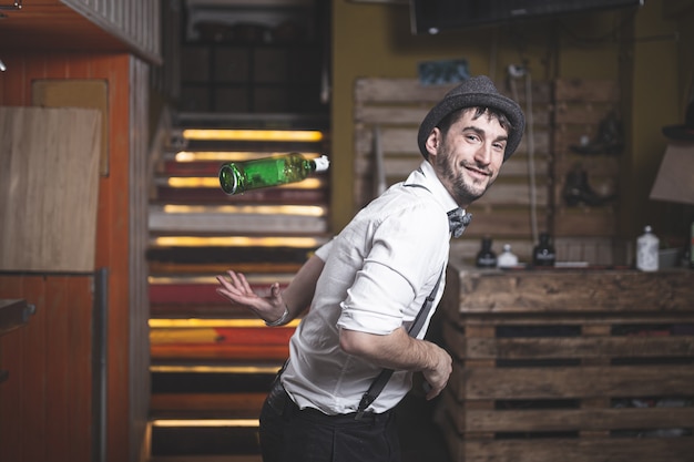 Barman especialista com chapéu e gravata borboleta jogando garrafa no ar Foto Premium