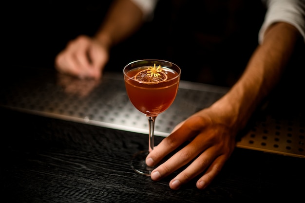 Barman servindo um coquetel no copo com uma fatia de limão caramelizado Foto Premium