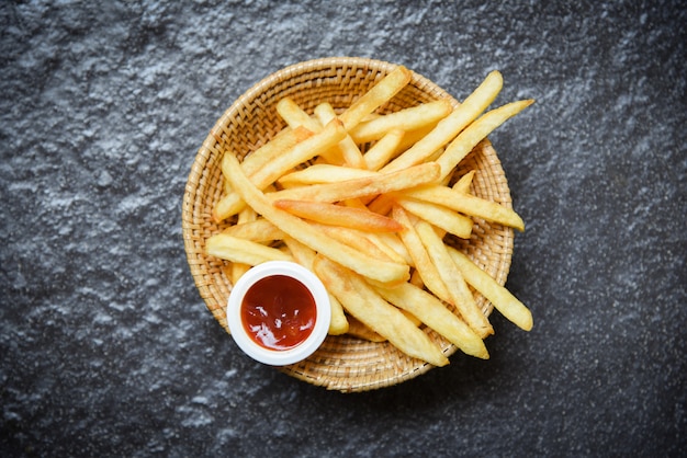 Batatas fritas na cesta com ketchup no escuro Foto Premium