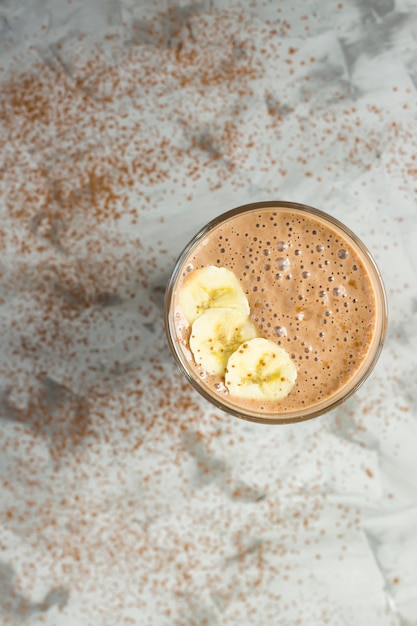 Batidos de chocolate-banana com cacau em um copo sobre um fundo cinza Foto Premium
