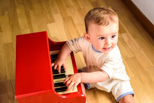 Bebê aprendendo a tocar piano com um instrumento de brinquedo de madeira, uma cena infantil tenra e engraçada. Foto Premium