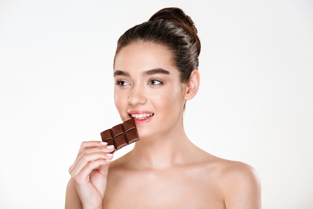 Bela imagem de mulher seminua com fome, com cabelos escuros, comendo barra de chocolate, não estar de dieta Foto gratuita