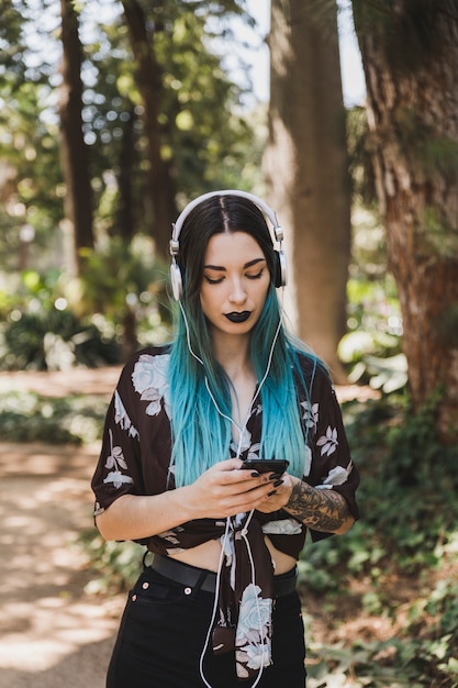 Bela jovem ouvindo música no fone de ouvido através do celular Foto gratuita