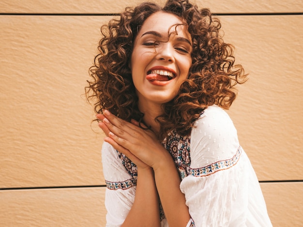 Bela modelo sorridente com afro cachos penteado vestido com vestido branco hipster de verão. Foto gratuita