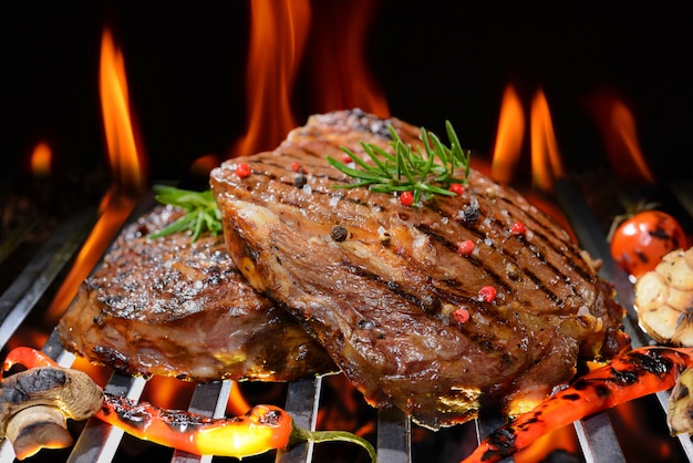 Bife grelhado com legumes na grelha flamejante | Foto Premium