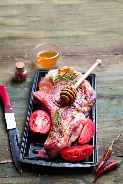 Bifes crus e frigideiras com temperos, guarnições e ingredientes Foto Premium
