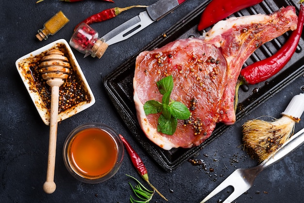 Bifes crus e frigideiras com temperos, guarnições e ingredientes Foto Premium