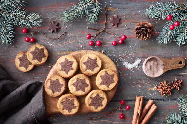 Biscoitos de natal com padrão de estrela de chocolate com estrelas de chocolate, canela e galhos de pinheiro decorado Foto Premium