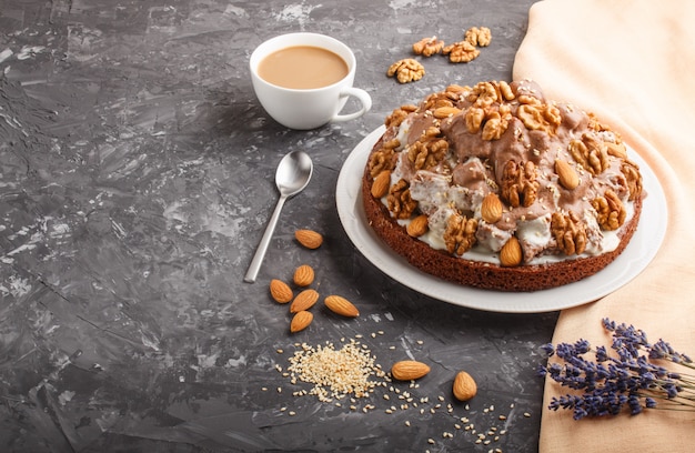 Bolo caseiro com creme de leite, cacau, amêndoa, avelã com têxteis laranja e uma xícara de café. vista lateral. Foto Premium