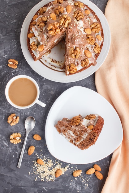 Bolo caseiro com creme de leite, cacau, amêndoa, avelã com têxteis laranja e uma xícara de café. vista superior, copie o espaço. Foto Premium