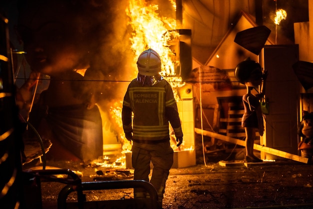 Bombeiros em torno de uma fogueira causada por um falla valenciana controlando as chamas do fogo. Foto Premium