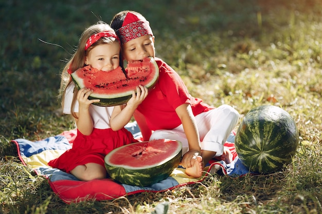 Bonitos crianças com melancias em um parque Foto gratuita