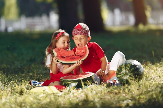 Bonitos crianças com melancias em um parque Foto gratuita