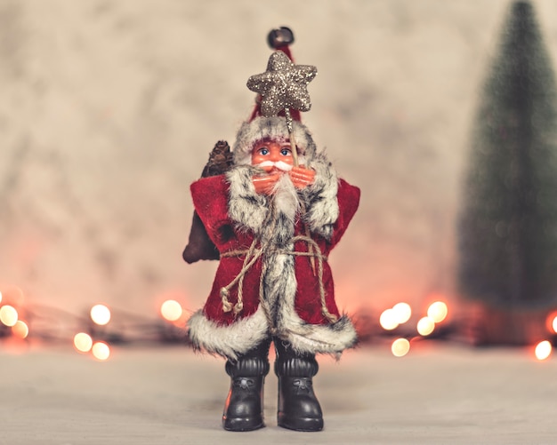 Brinquedo de papai noel tem uma equipe com uma estrela e uma árvore de natal em um fundo Foto Premium
