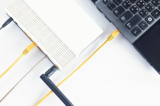 Cabo de modem e lan conectando com laptop na mesa Foto Premium