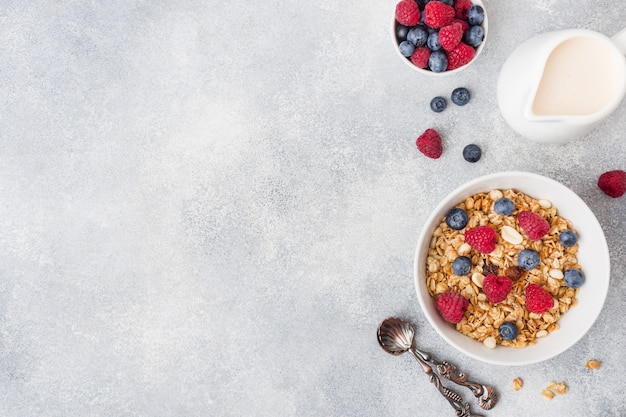 Café da manhã saudável. granola fresco, muesli com iogurte e bagas no fundo cinzento. Foto Premium
