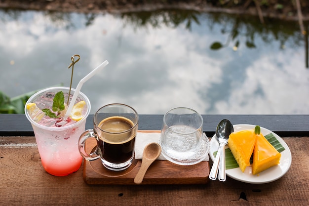 Café fresco em um copo e suco de lichia e bolo de laranja misturado com limão Foto Premium