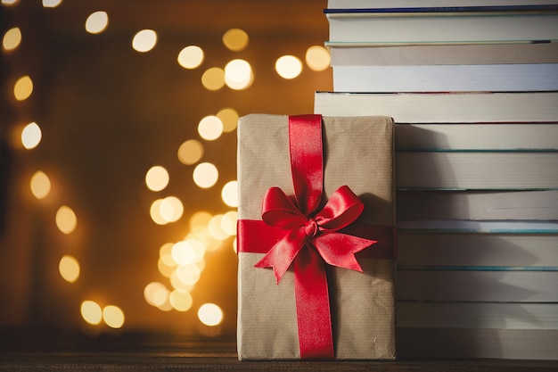 Caixa de presente de natal e pilha de livros com luzes de fada Foto Premium