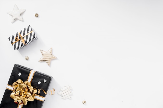 Caixa de presente ou presente, chapéus de festa e estrelas na mesa branca. composição de natal com enfeites pretos e dourados Foto Premium