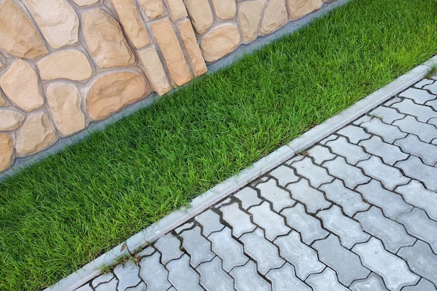 Calçada pavimentada com tijolos de cimento e gramado com grama verde Foto Premium