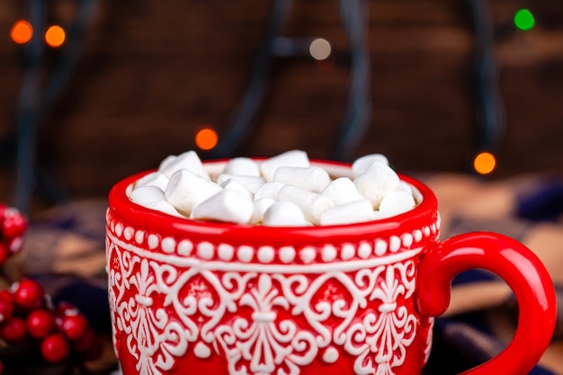 Caneca com cacau e marshmallows com fundo de luzes de guirlanda de natal aconchegante Foto Premium